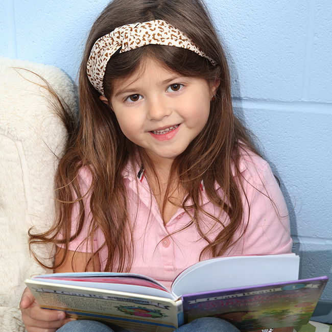 Little girl smiling at the camera with a book